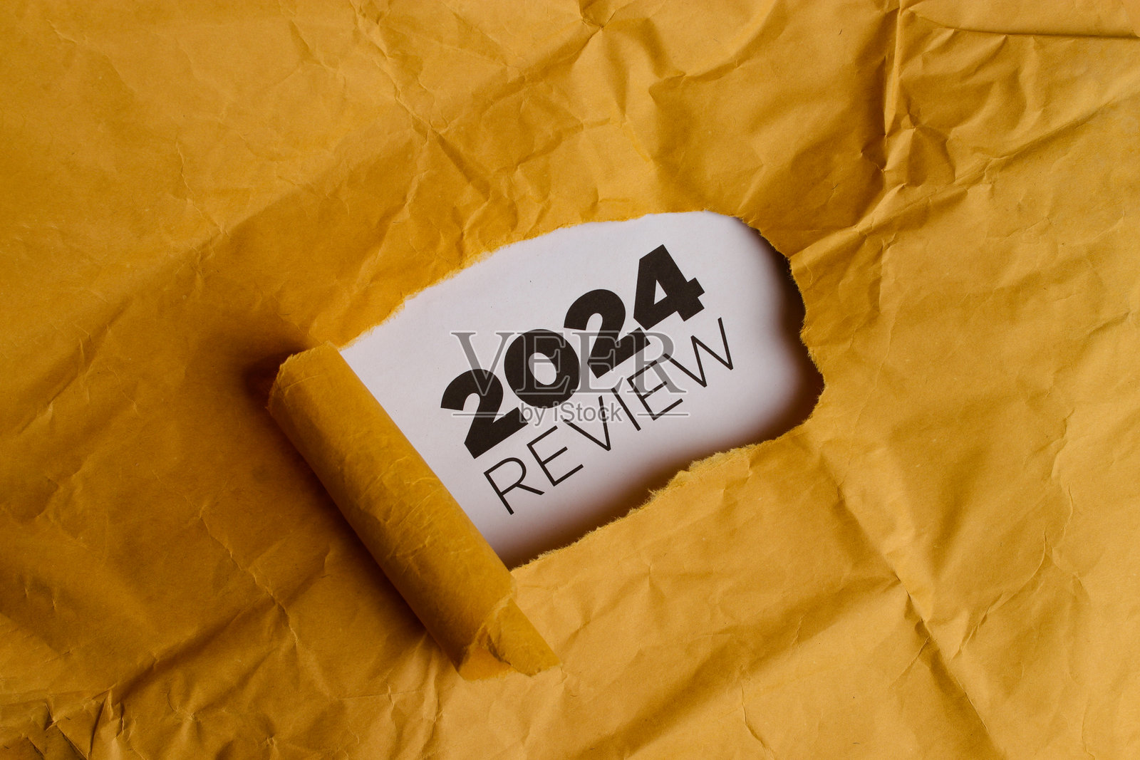 黄色纸张上有一个孔，露出“2024年回顾”字样照片摄影图片