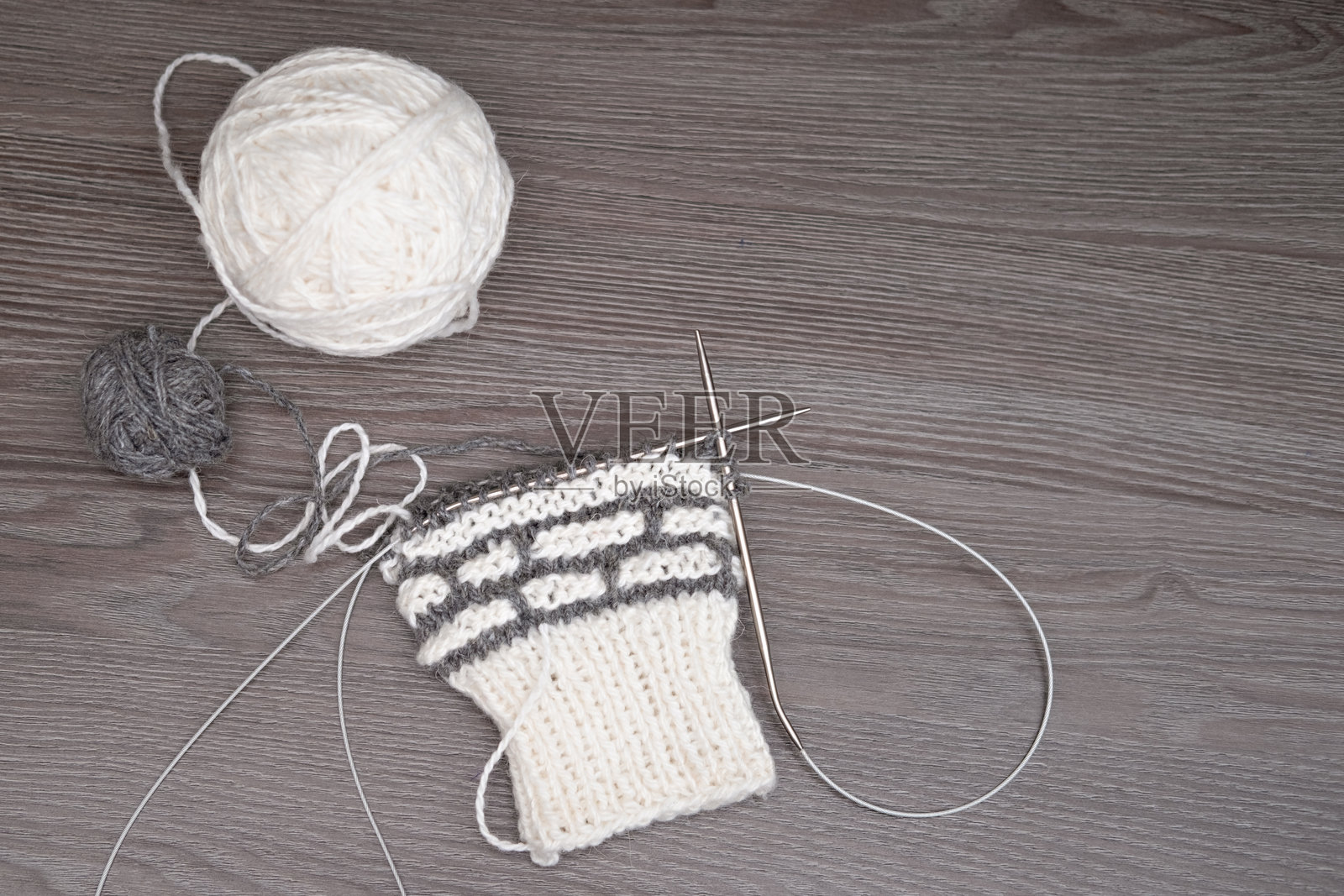 一团毛线和一双针织针放在浅色背景上照片摄影图片