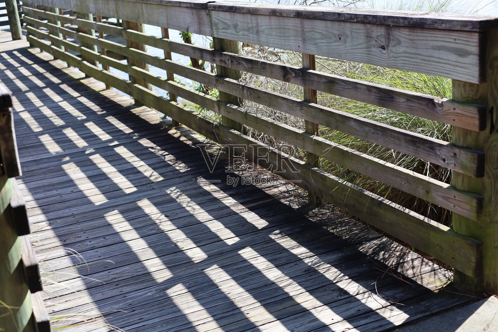 木栈道横跨水面，投下阴影照片摄影图片