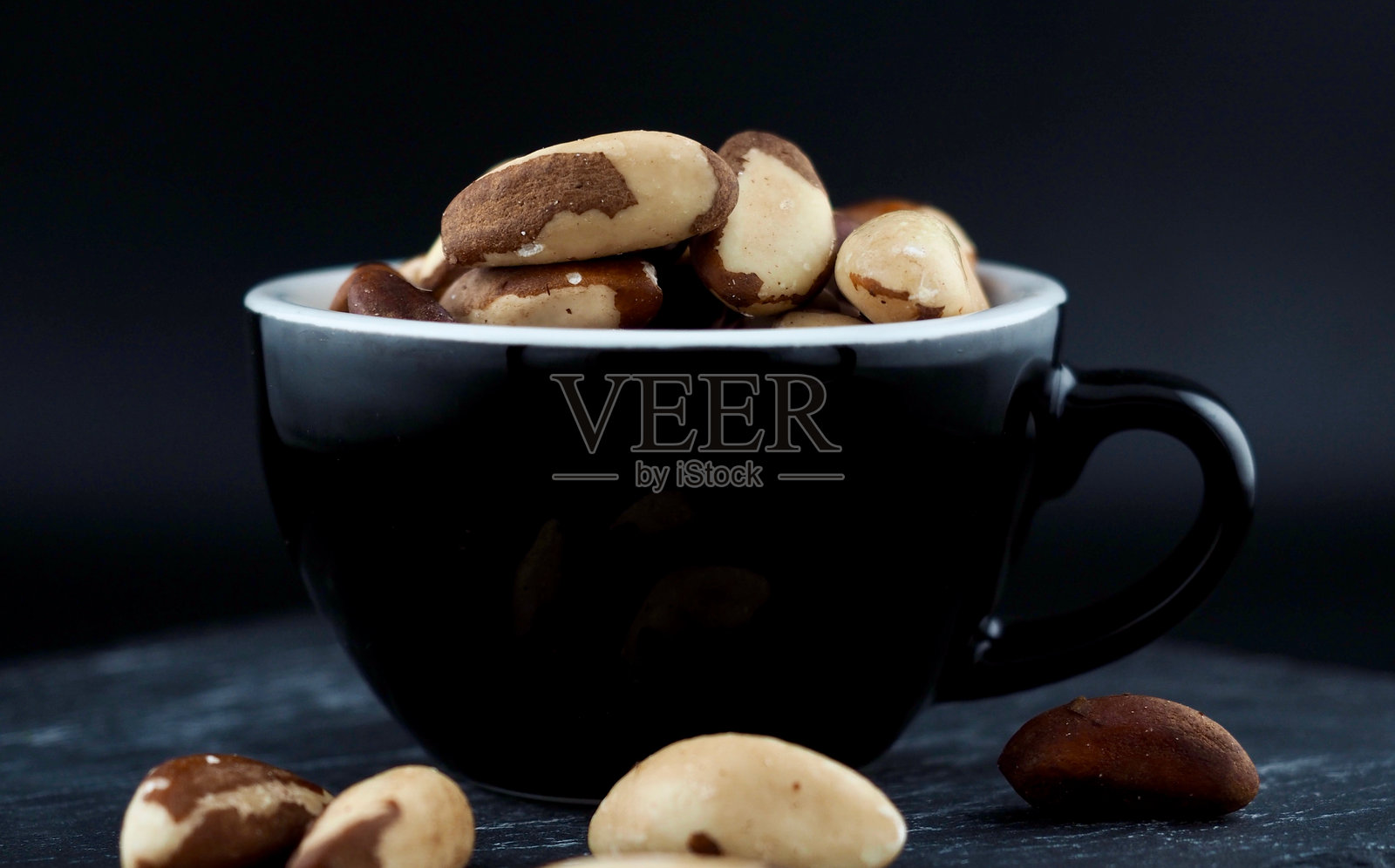 黑色瓷杯中的巴西坚果照片摄影图片