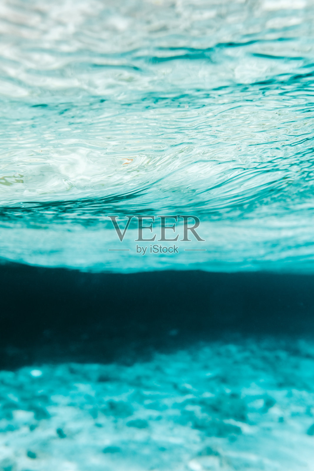 阳光明媚的马尔代夫热带岛屿上的绿松石沙滩泻湖，沙地上有阳光光晕的图案。照片摄影图片