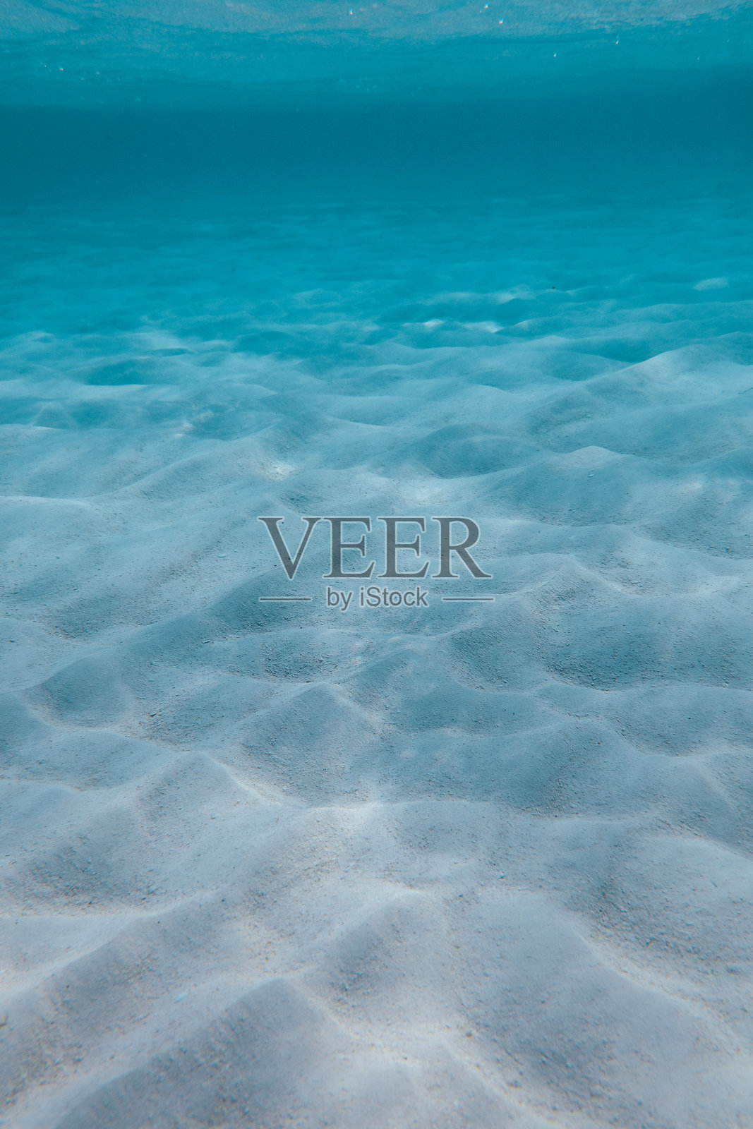 阳光明媚的马尔代夫热带岛屿上的绿松石沙滩泻湖，沙地上有阳光光晕的图案。照片摄影图片