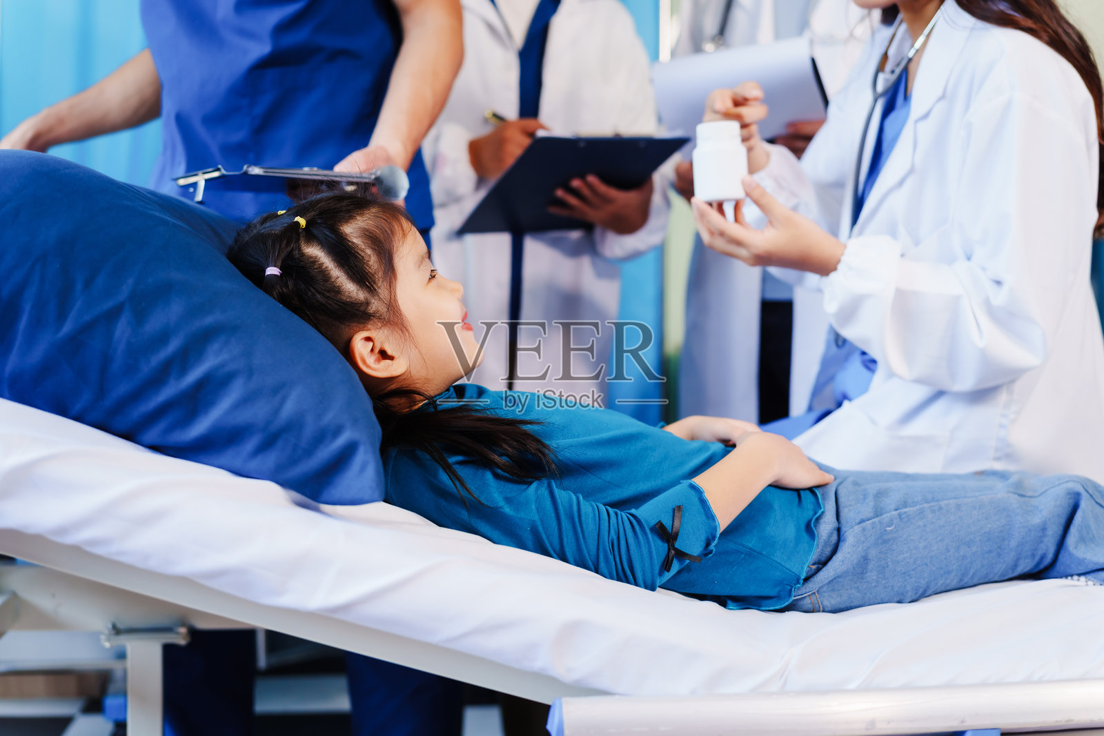 一位医生在医院的床上用听诊器听一个小女孩的心跳，医生正在进行例行检查以监测她的健康状况。照片摄影图片