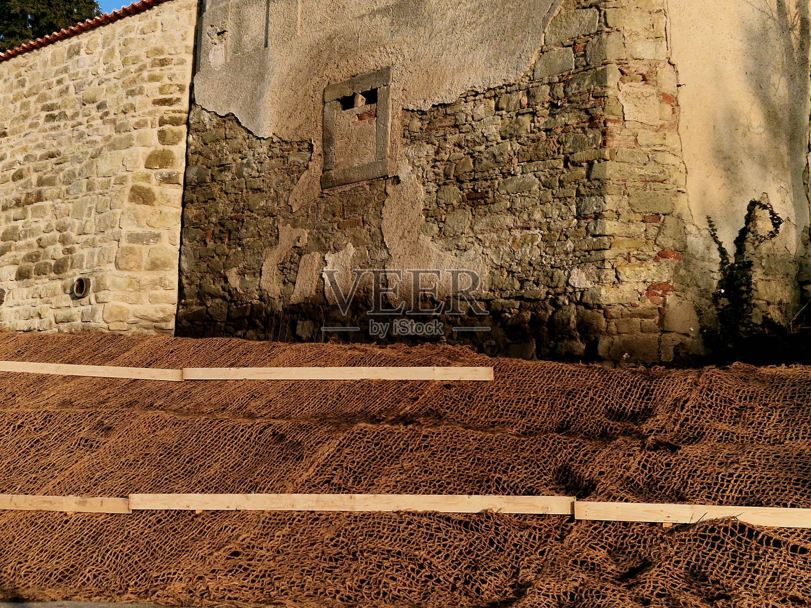 长直的混凝土搅拌机模板支撑墙。墙后是通过排水管排出的土壤。排水管道与下水道管道成一直线。建筑工地，墓地，石笼。照片摄影图片