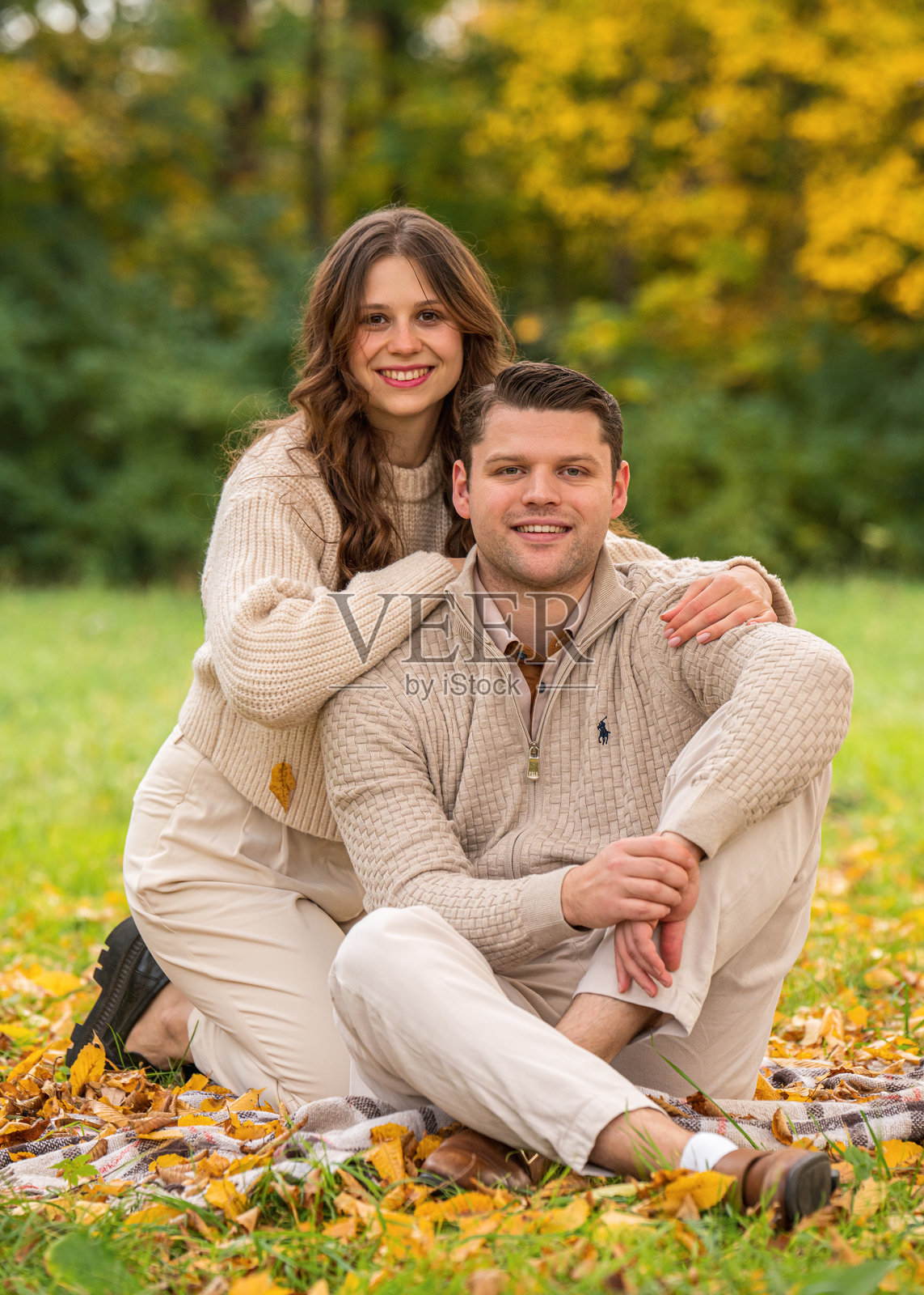 美丽快乐的情侣在秋天的树林中拥抱微笑，享受野餐时光。照片摄影图片