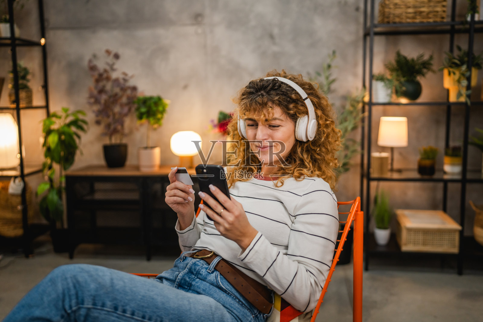 佩戴耳机的成年女性使用手机和信用卡进行支付照片摄影图片