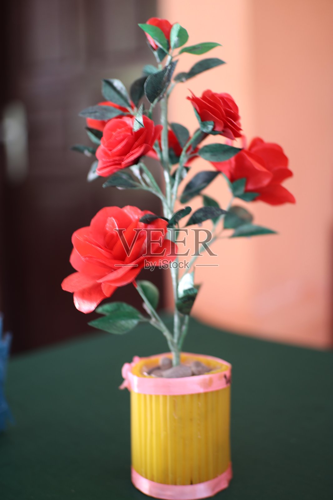 人工红玫瑰花艺装饰在黄色花盆中照片摄影图片