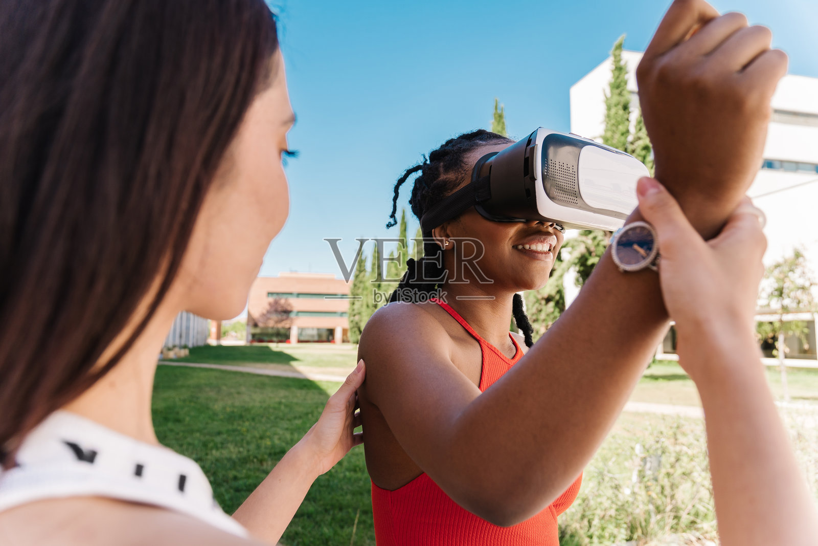 快乐的学生在大学校园里戴着虚拟现实眼镜，与女性朋友一起。照片摄影图片