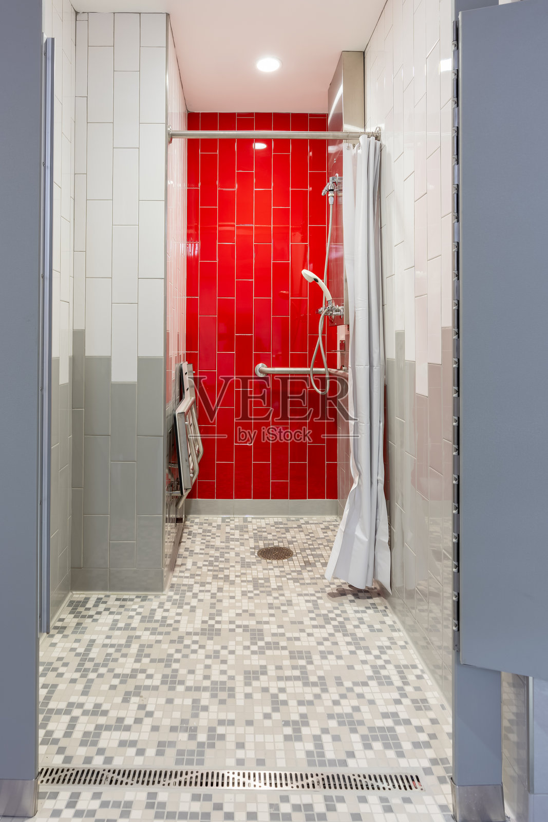 新单人私人健身房更衣室淋浴的竖直照片，红色瓷砖墙、长椅、瓷砖地板和白色淋浴帘。照片摄影图片