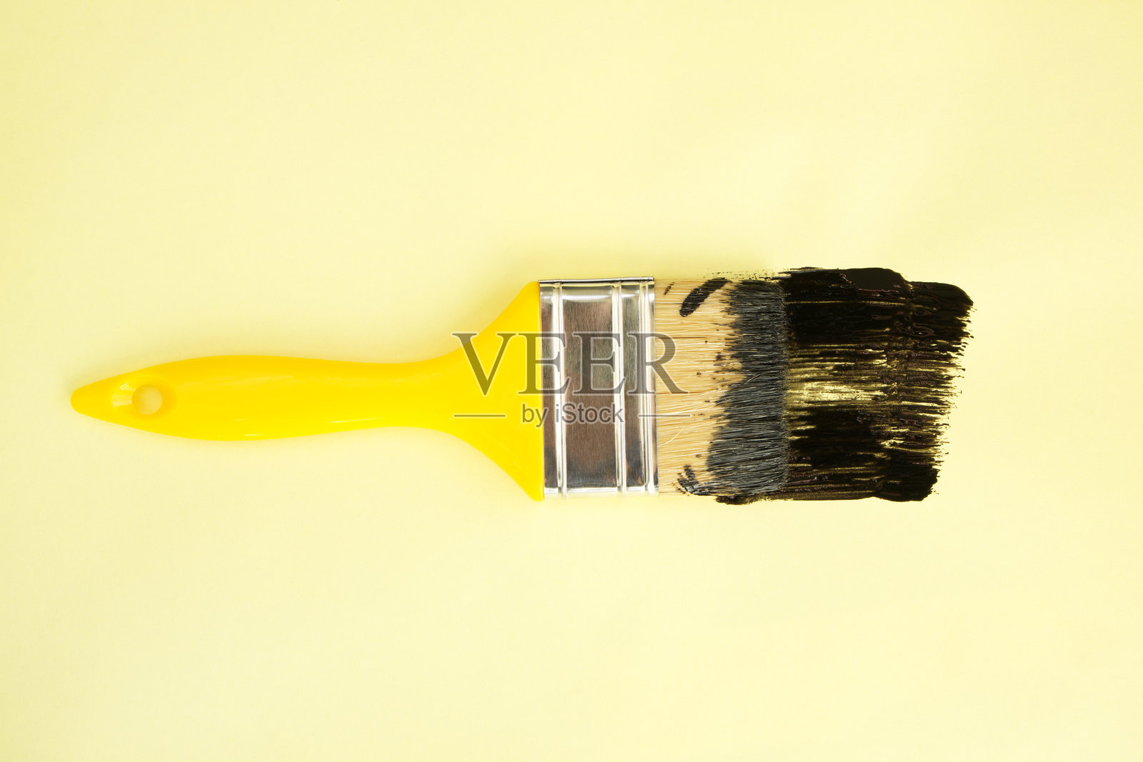 黑色油漆的画笔在黄色背景上照片摄影图片