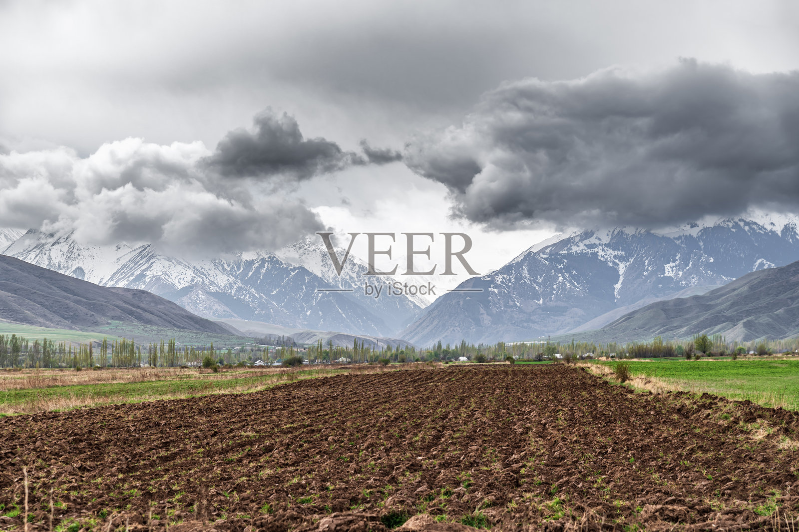 春天的山谷中耕耘的田地，山上云雾缭绕。照片摄影图片