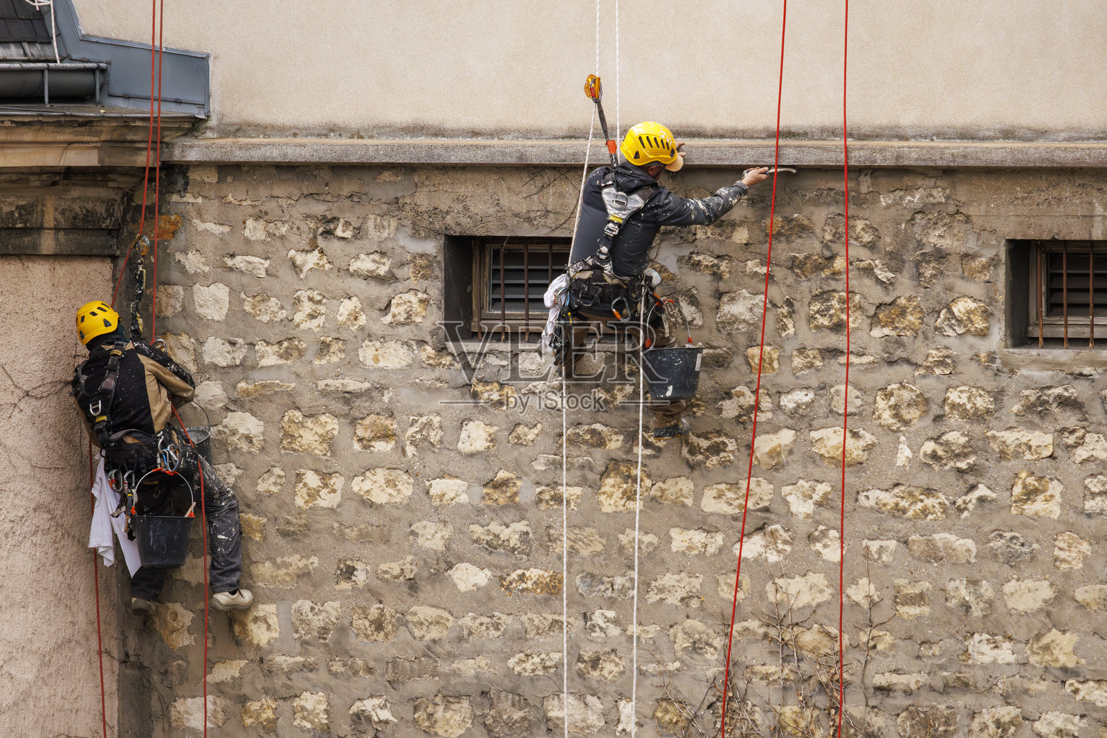 两名绳索作业工人在巴黎翻新建筑外立面照片摄影图片