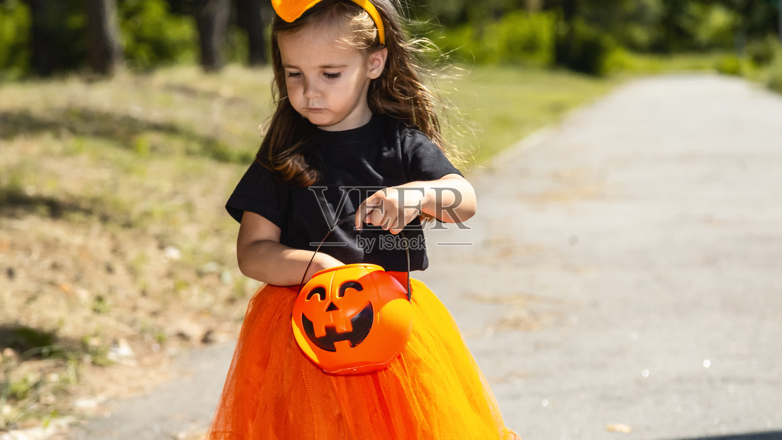 万圣节的孩子们。一位美丽可爱的女孩穿着女巫服装，戴着帽子。照片摄影图片