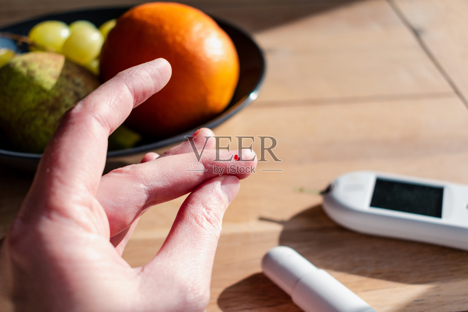 女性用血糖仪刺破手指检查血糖水平，测试糖尿病血糖。照片摄影图片