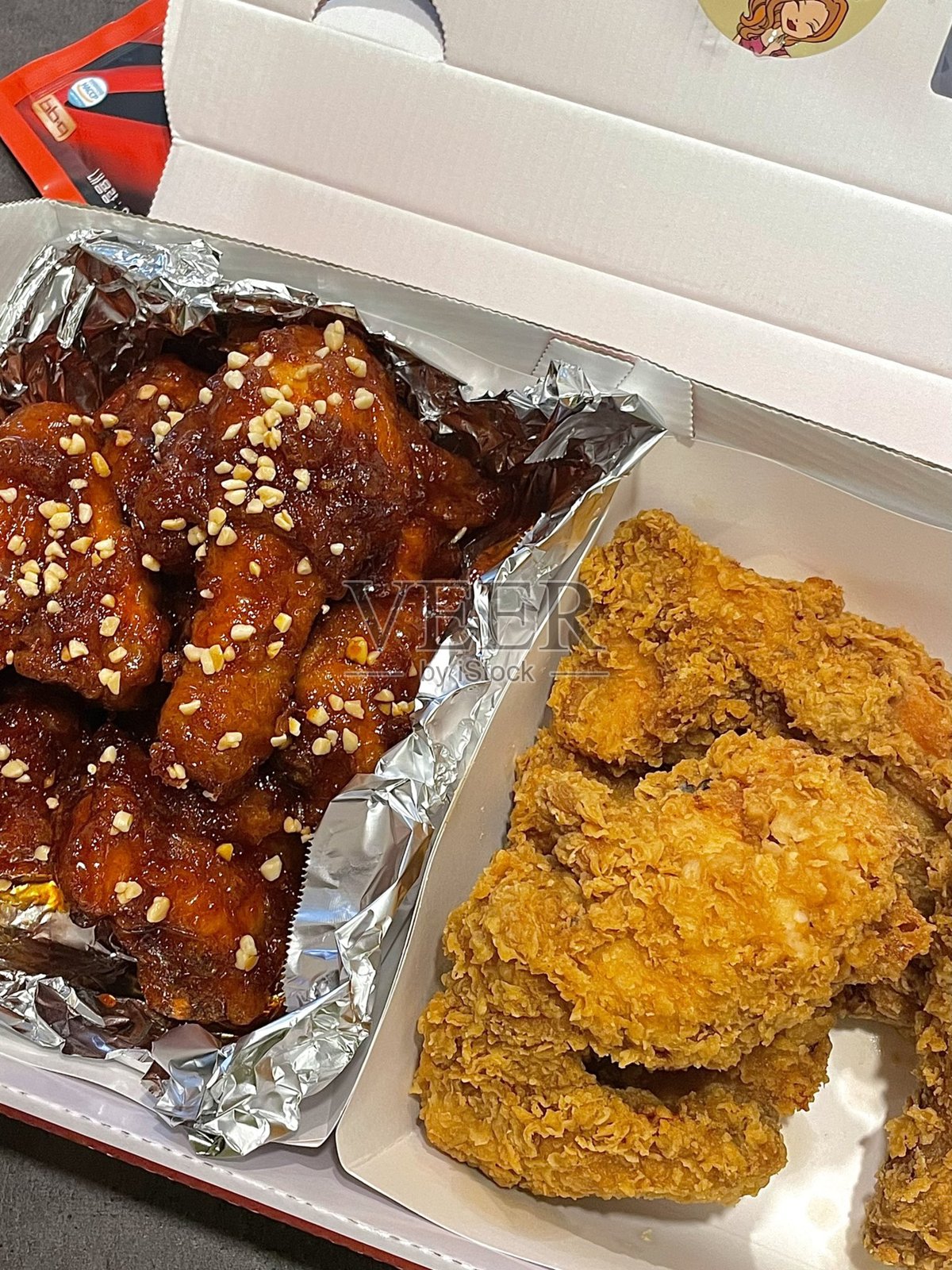 酥脆的韩国炸鸡，完美地涂上甜辣酱。非常适合食品摄影和菜单，展现这道受欢迎菜肴的不可抗拒的脆感和风味。照片摄影图片