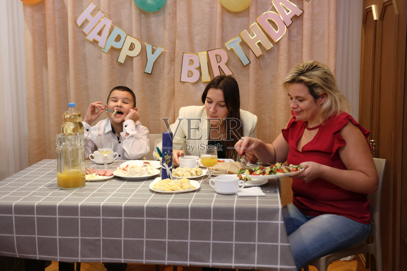 庆祝男孩的生日，客人们坐在桌旁，喝酒享受美食。生日庆祝活动。照片摄影图片