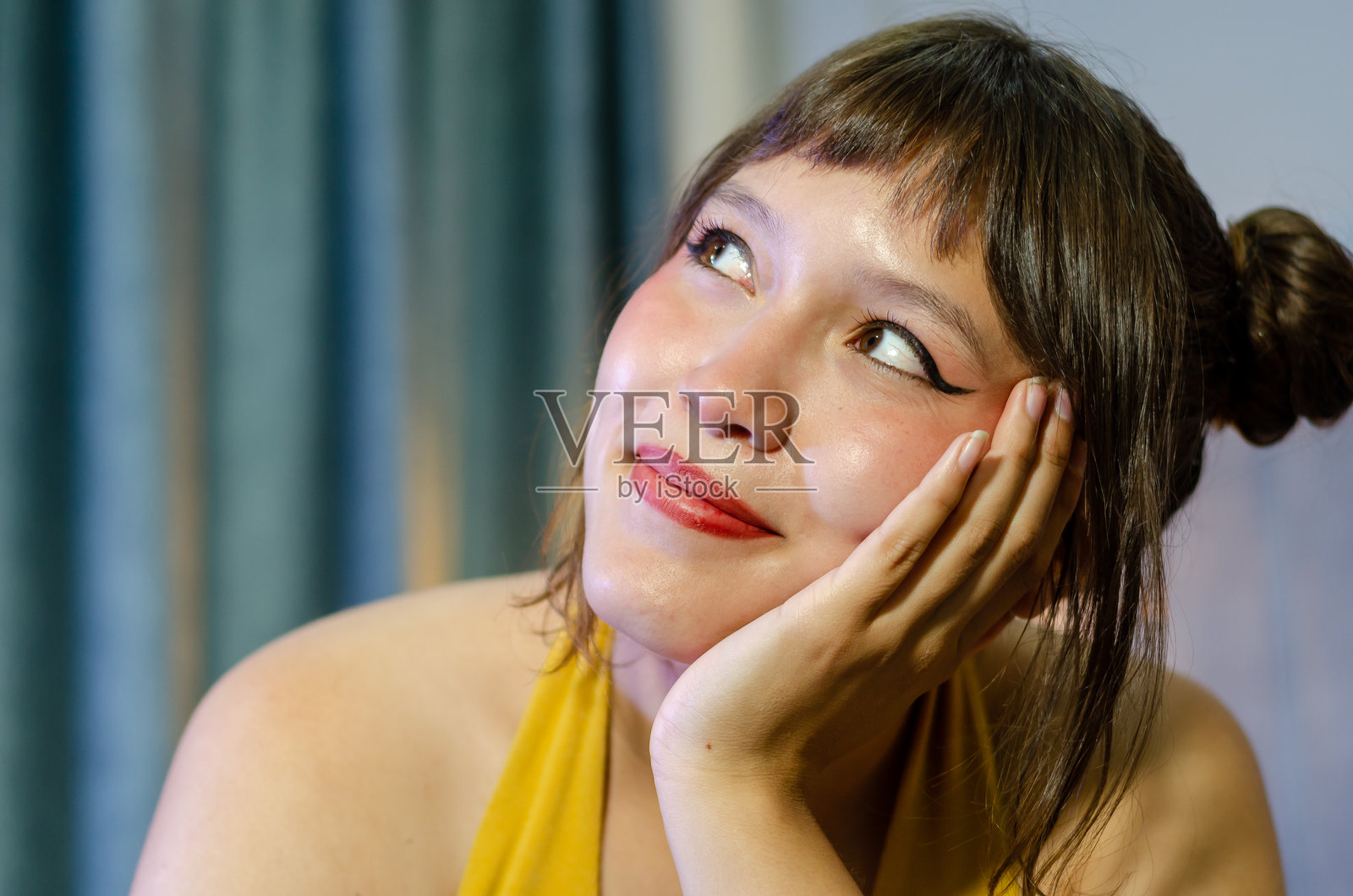 美丽年轻女子的特写肖像，棕色头发和双马尾，坐在卧室的床上。照片摄影图片