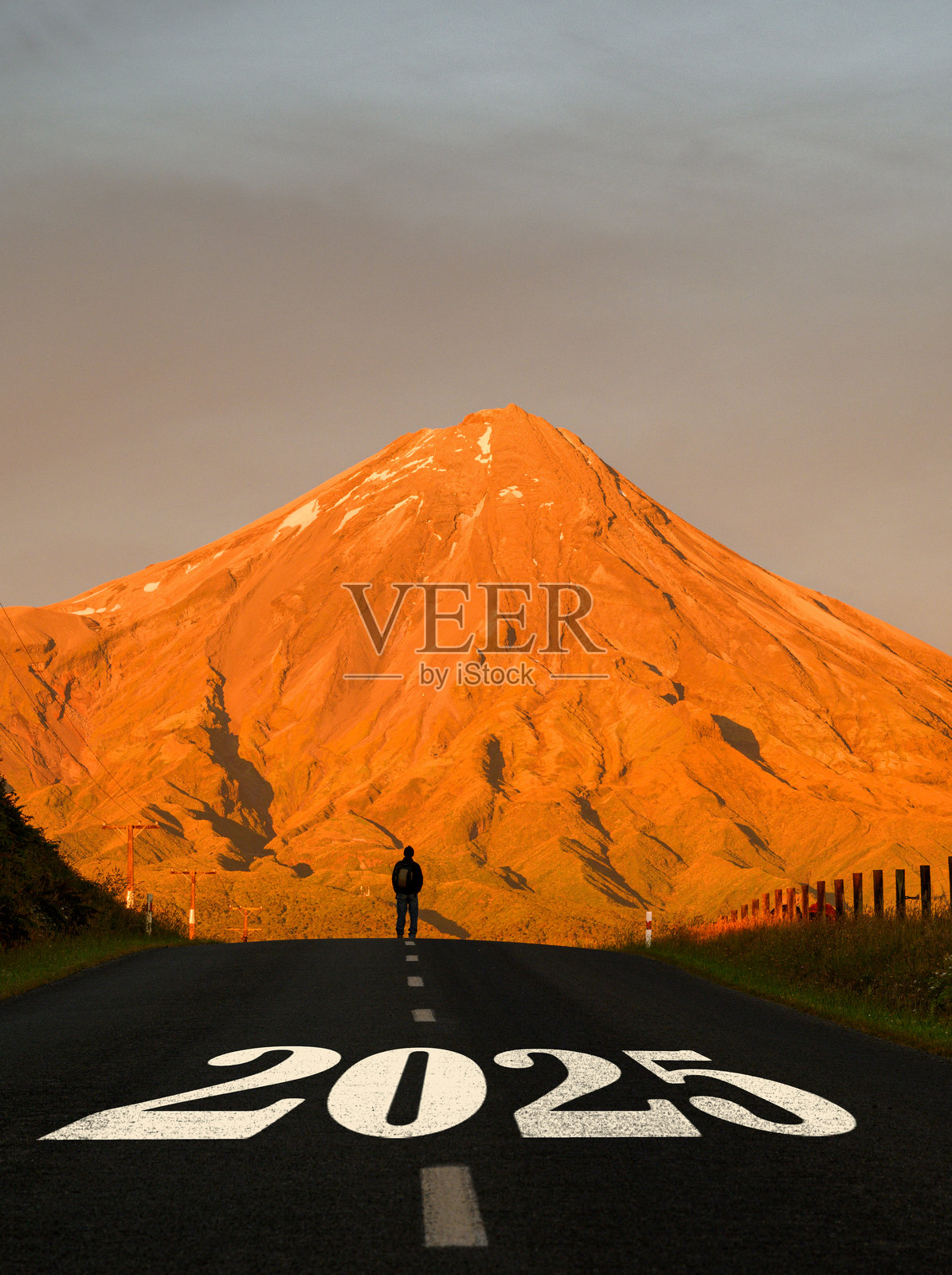 2025年新年。2025的字样写在通往塔拉纳基山的道路上。一个人站在道路的顶端。新西兰。照片摄影图片