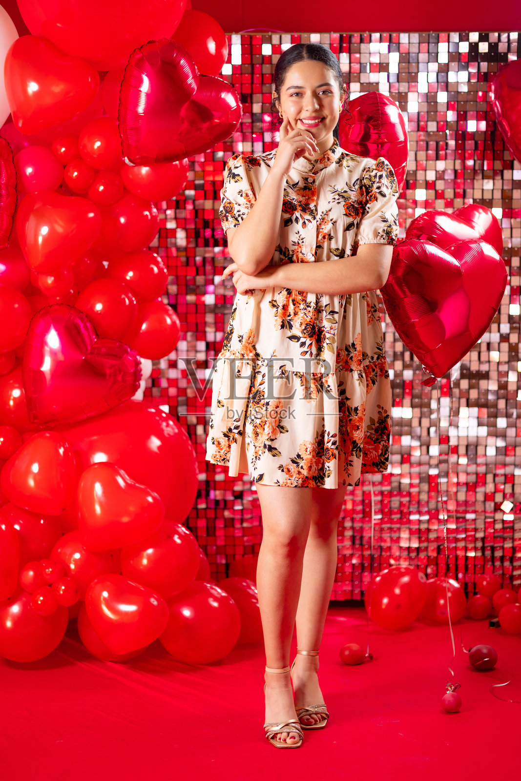 穿着休闲裙的美丽年轻女性在摄影棚中与氦气心形气球摆姿势照片摄影图片