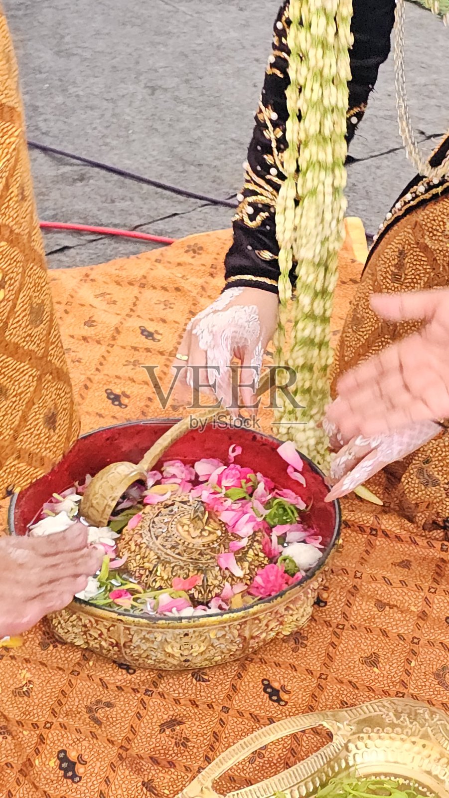 爪哇印尼传统仪式，Ranupada或Wijikan，在这个仪式中，新娘将用花瓣水洗新郎的脚。这一过程象征着妻子对丈夫的奉献和丈夫对妻子的保护。照片摄影图片