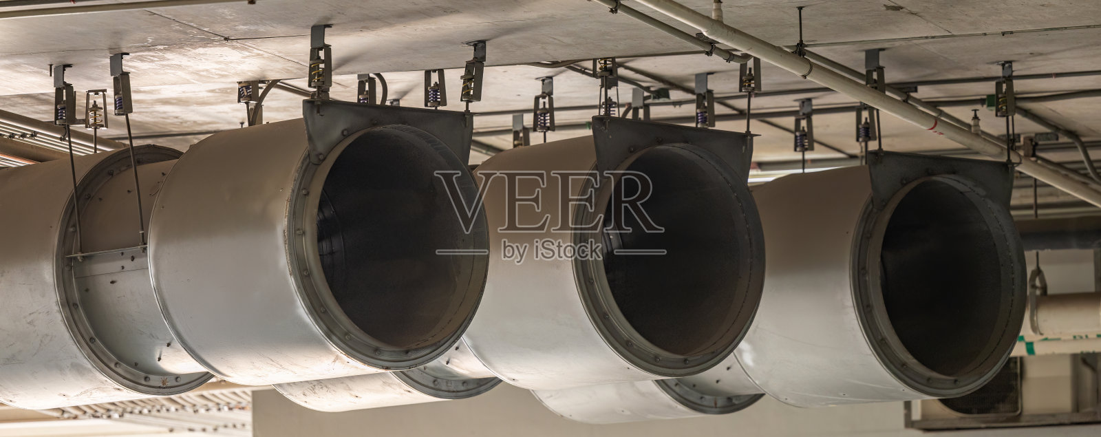 现代建筑内的风扇。停车场通风系统。鼓风机为工厂的密闭空间提供空气流动。工业风扇加热器和冷却器。照片摄影图片