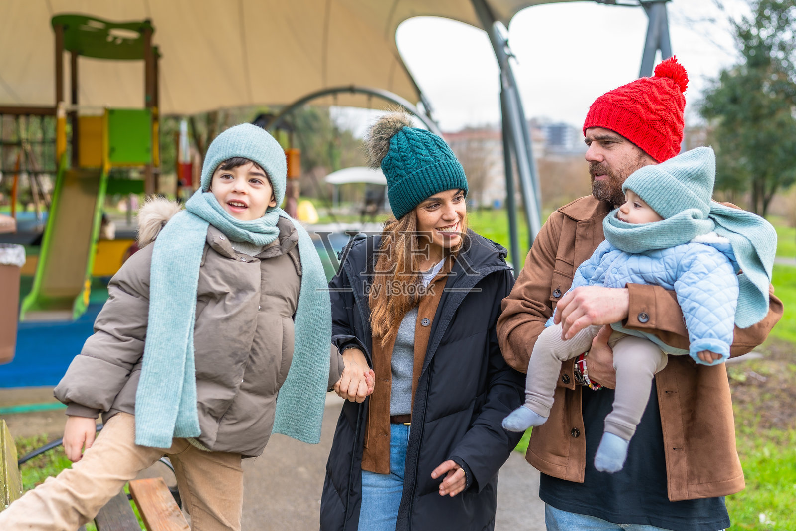 快乐的家庭在冬季的游乐场散步照片摄影图片