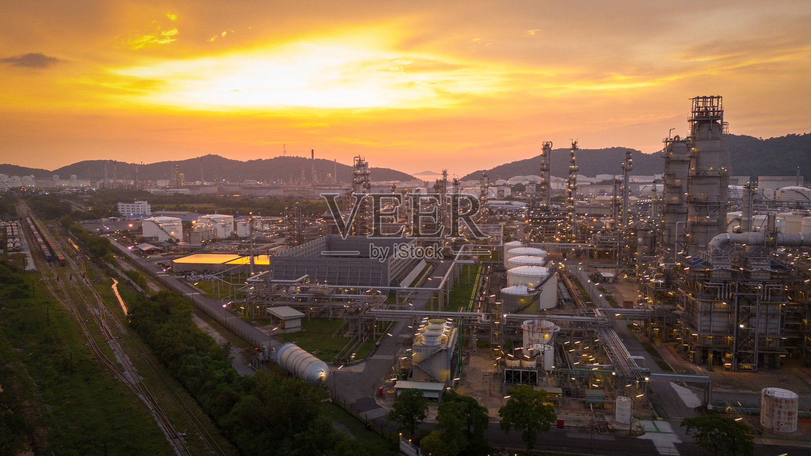 日落时的石油炼油厂。气体化学设备生产进出口概念，原油炼油厂的钢制泵管道、烟囱和冷却塔，化学石油化工。照片摄影图片