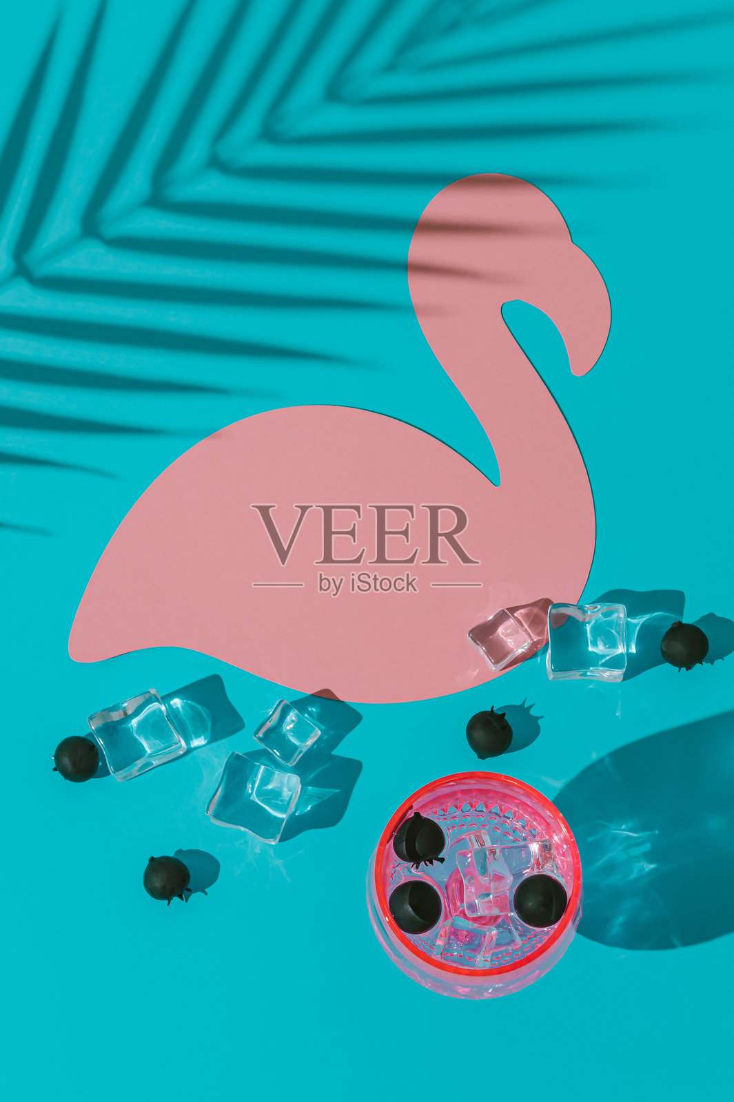 夏日场景，热带清爽饮品与棕榈树阴影，蓝色背景上有粉色火烈鸟纸卡片。阳光与阴影。极简鸡尾酒概念。时尚派对创意。创意留白。照片摄影图片