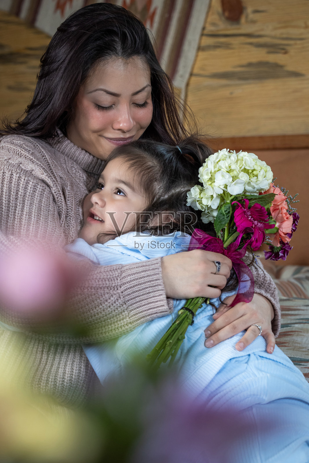 一位年轻母亲手捧着女儿送的花束。照片摄影图片