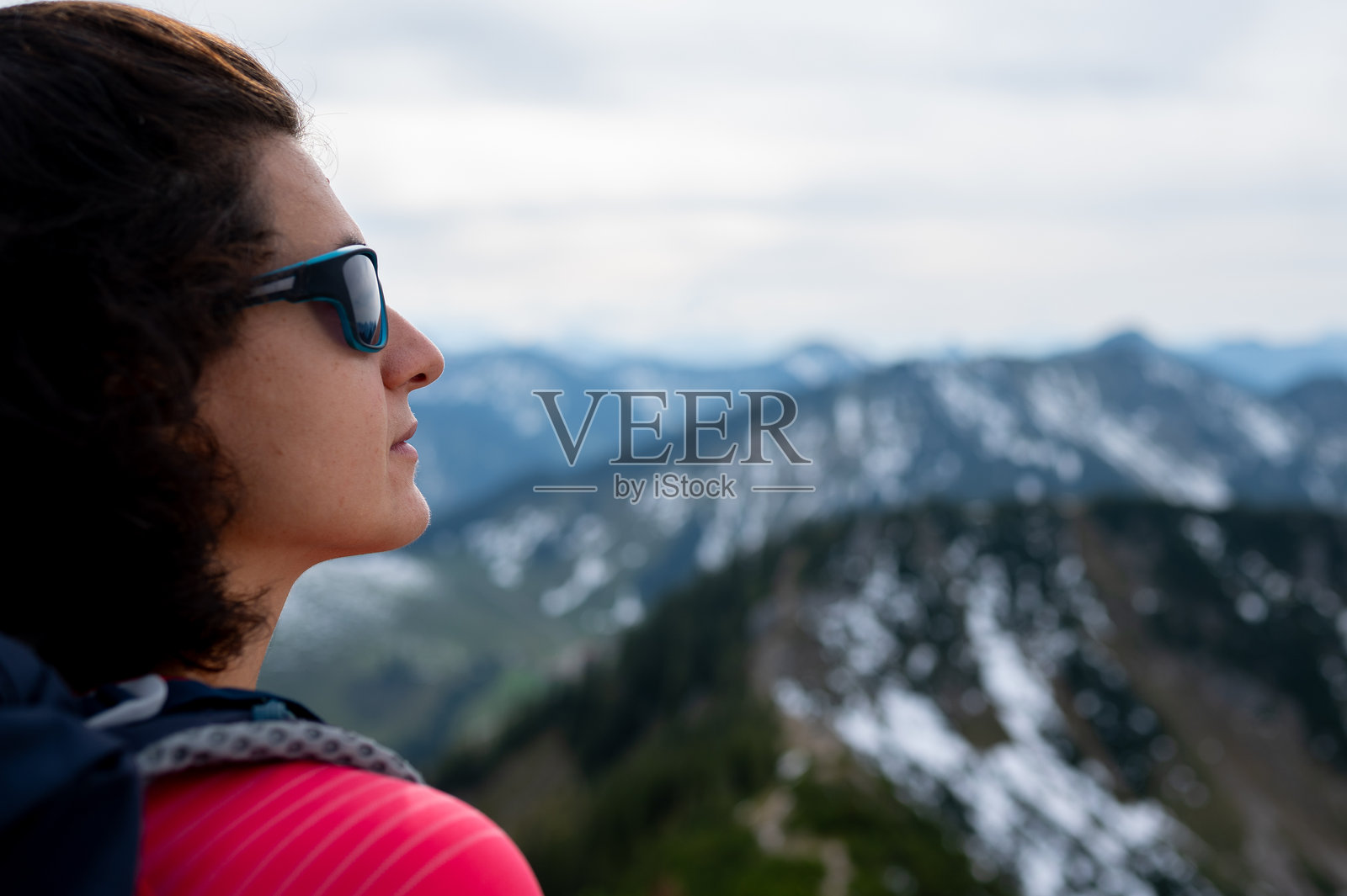 女性徒步旅行者的头部特写，背景是模糊的雪山全景。照片摄影图片