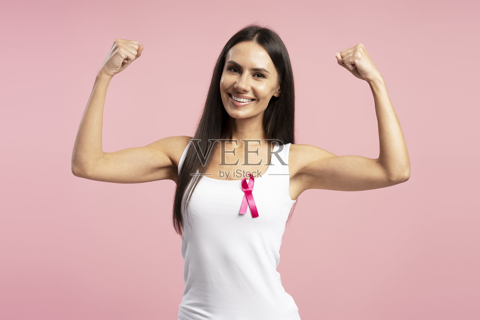 微笑的中年女性展示二头肌，佩戴粉色乳腺癌意识丝带照片摄影图片