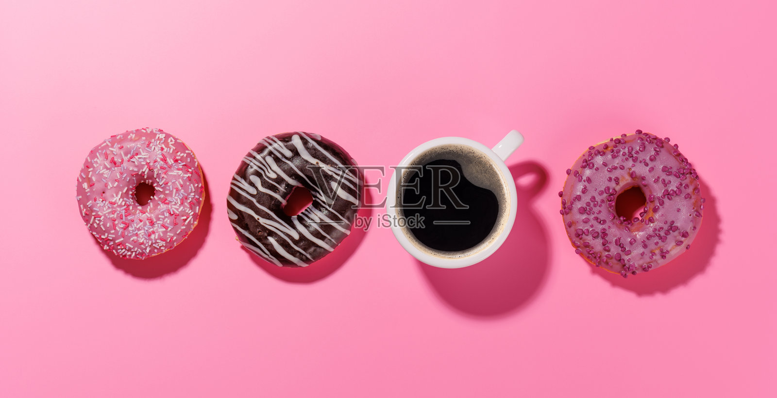 一组色彩鲜艳的甜甜圈，上面装饰着五彩缤纷的配料，还有一杯咖啡。照片摄影图片