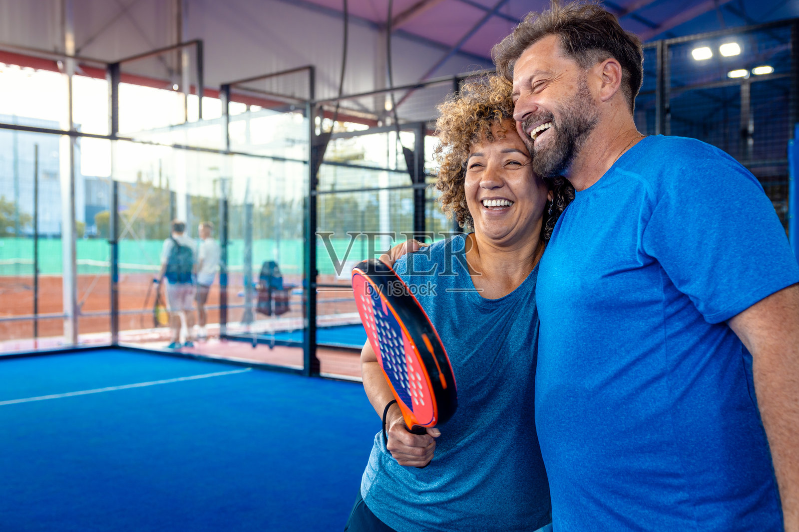 混合成年情侣在户外场地庆祝赢得了壁球的得分。照片摄影图片