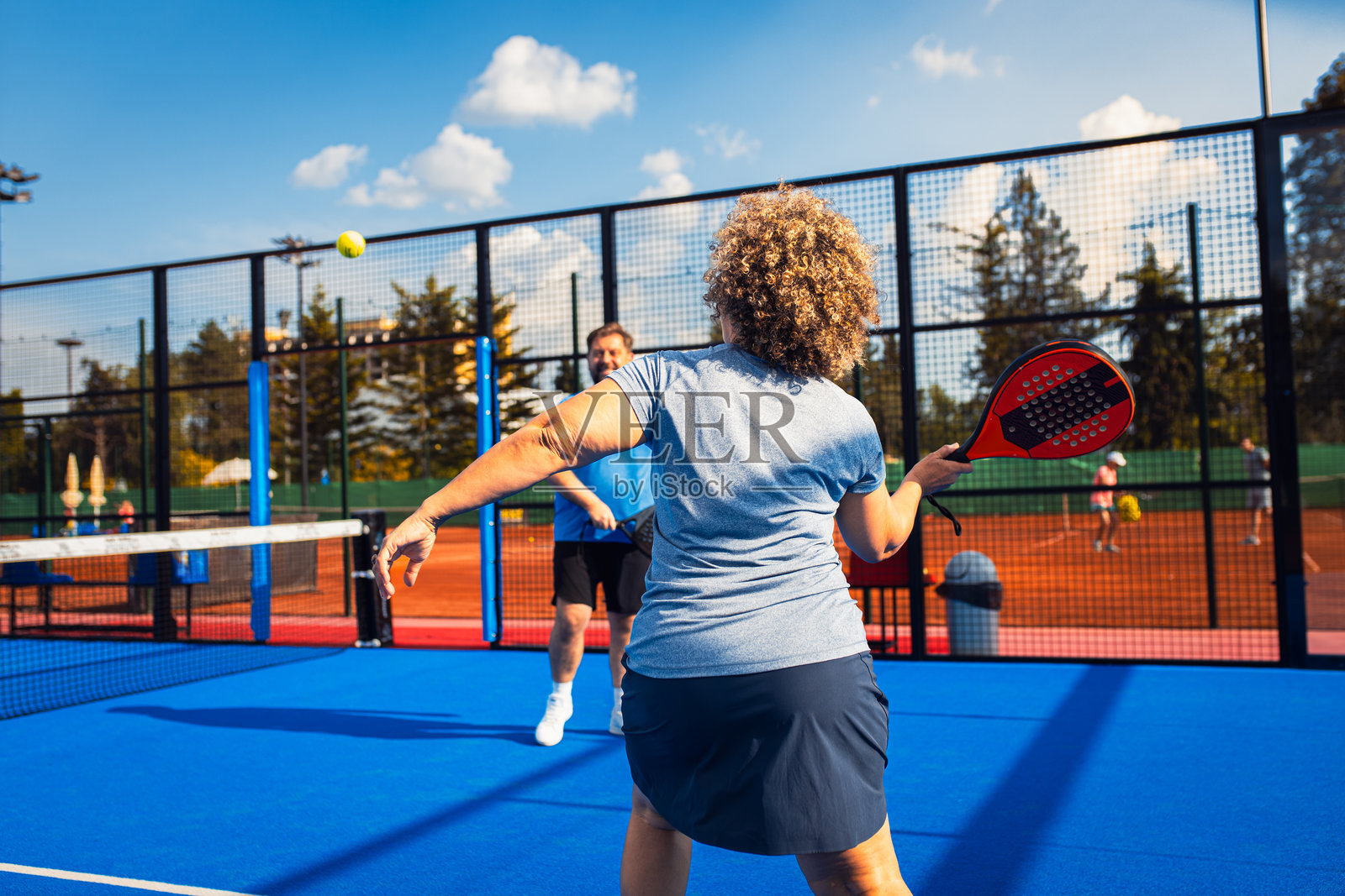 混合成年情侣在户外场地打壁球。照片摄影图片