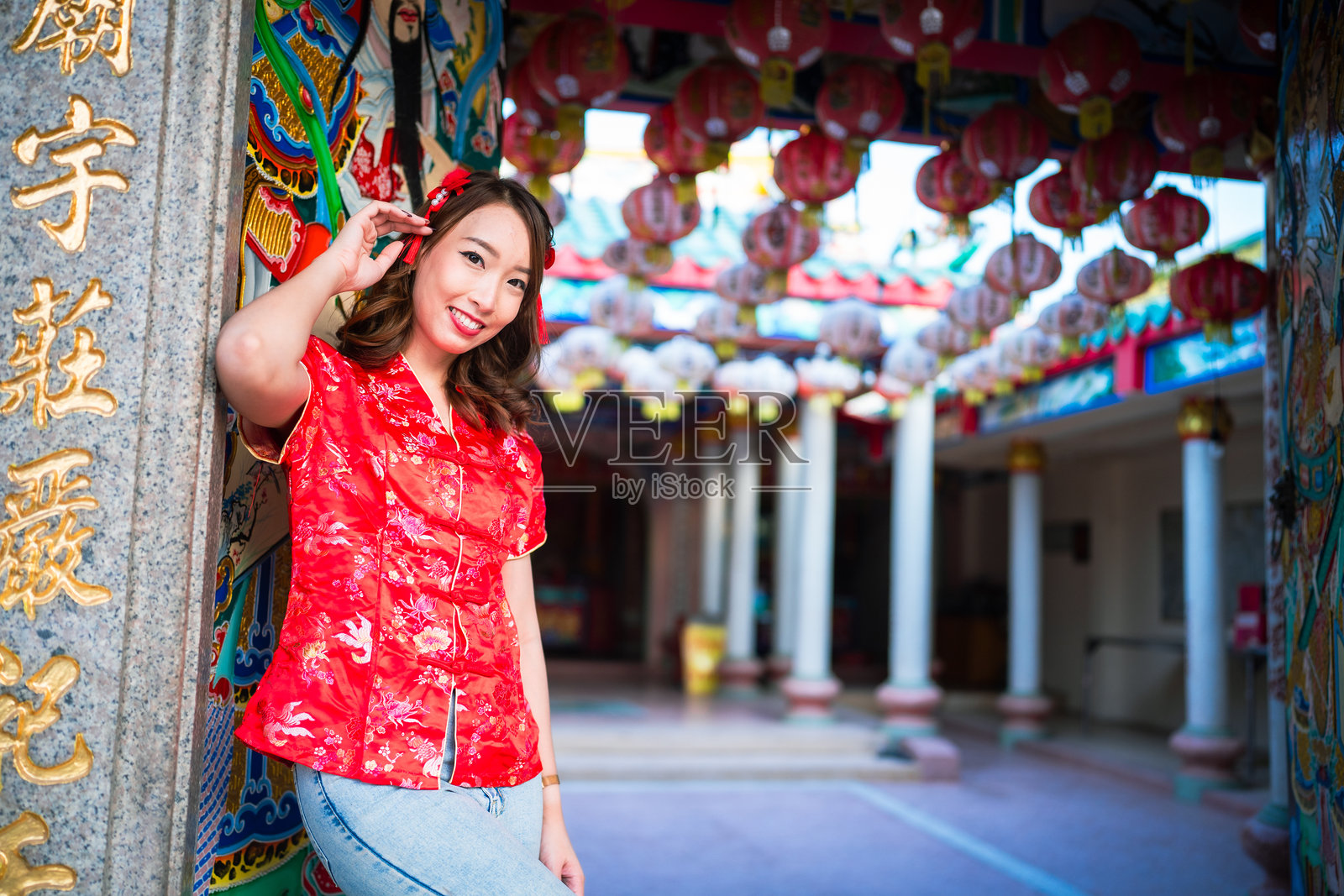 一位穿着红色衬衫的女性在一栋带有中文书写的建筑前摆姿势照片摄影图片