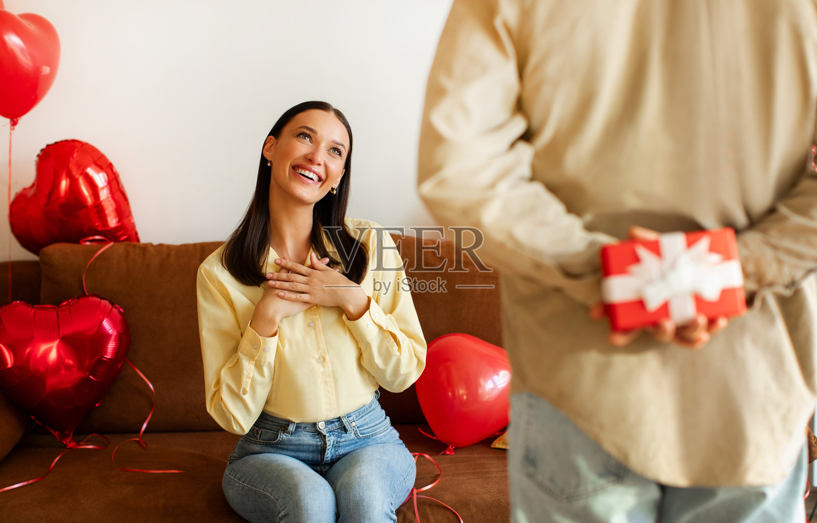 快乐的夫妻在家庆祝情人节，男人把礼物盒藏在背后，给妻子制造惊喜。照片摄影图片