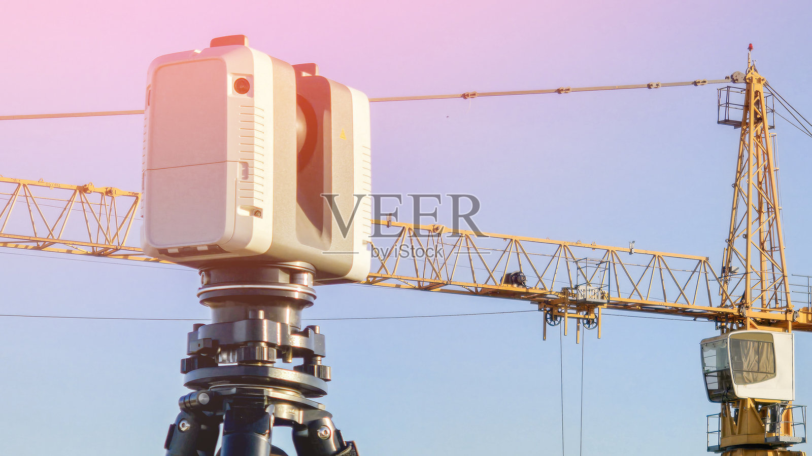 建筑工地激光扫描的测绘3D扫描仪，背景是建筑起重机和蓝天。照片摄影图片