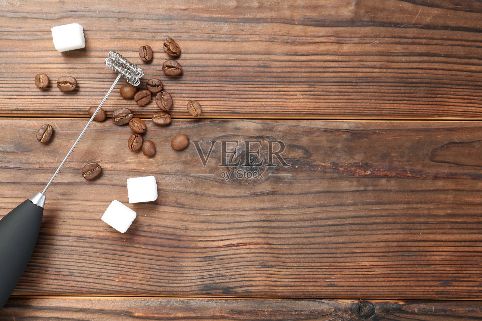 黑色奶泡器、糖块和咖啡豆在木桌上的平铺布局，留有文字空间照片摄影图片