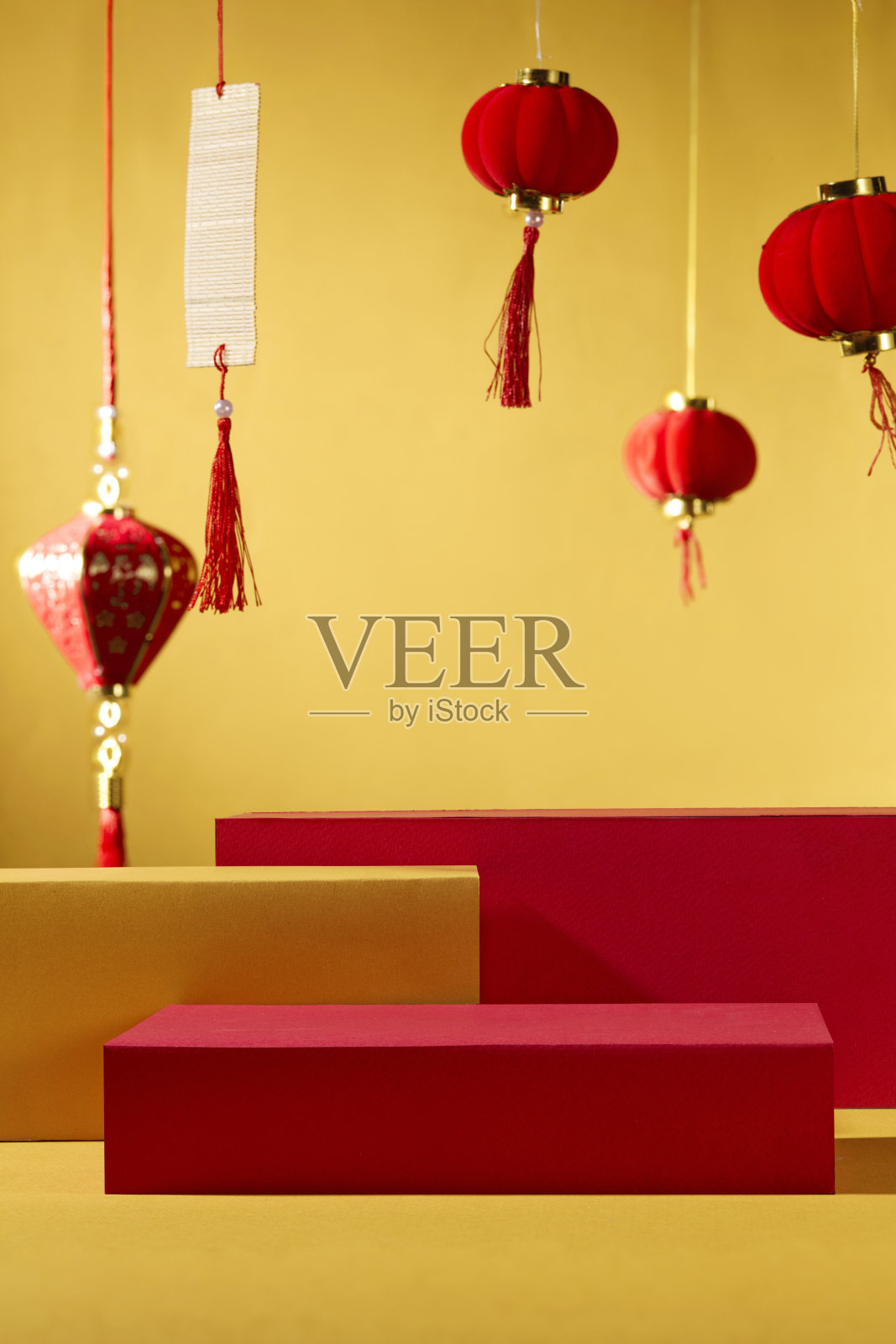 传统的新年概念。几个圆柱形底座用于在金色背景前展示产品。装饰有中国灯笼和书法。照片摄影图片