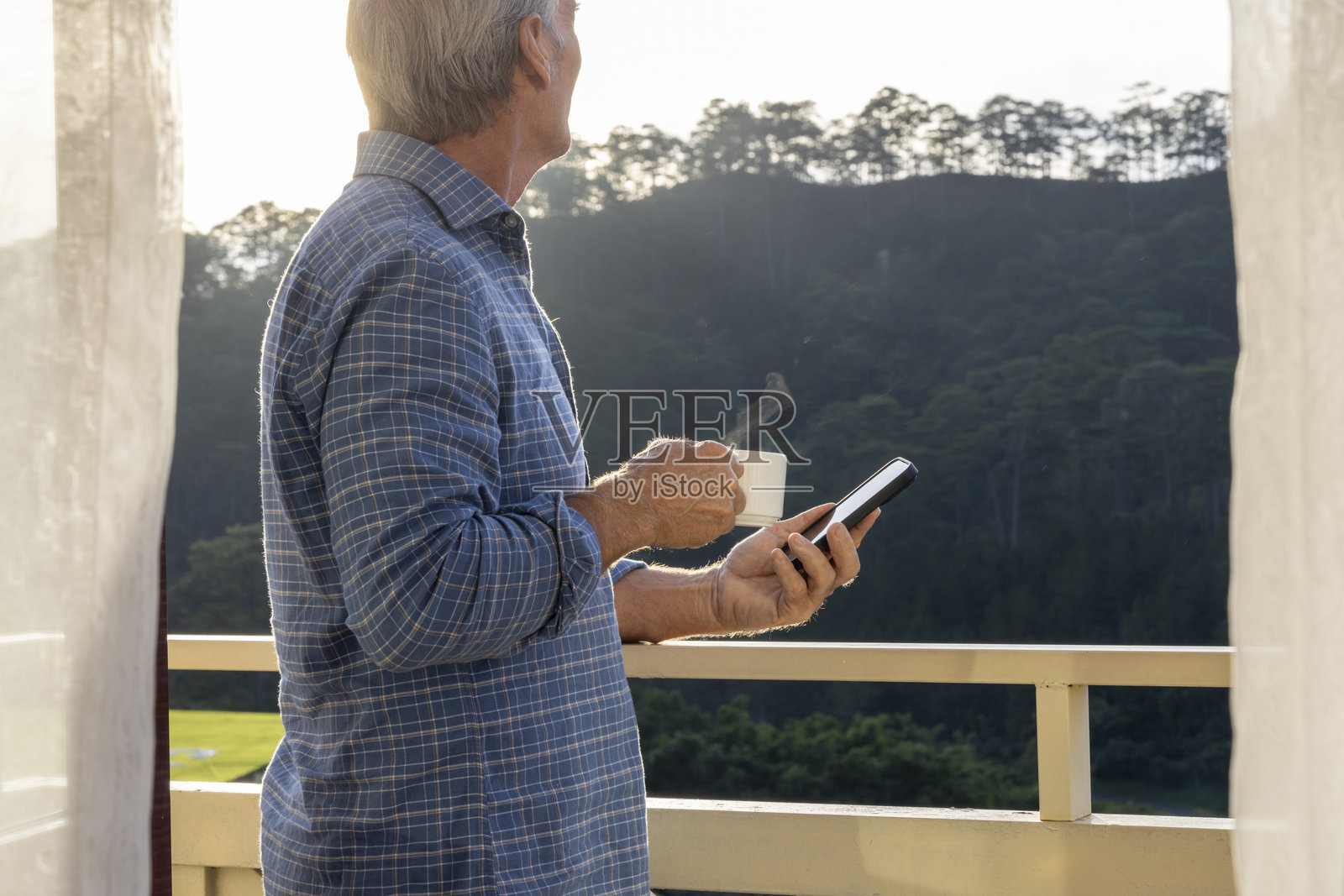 男性在日出时分的门廊上使用手机照片摄影图片