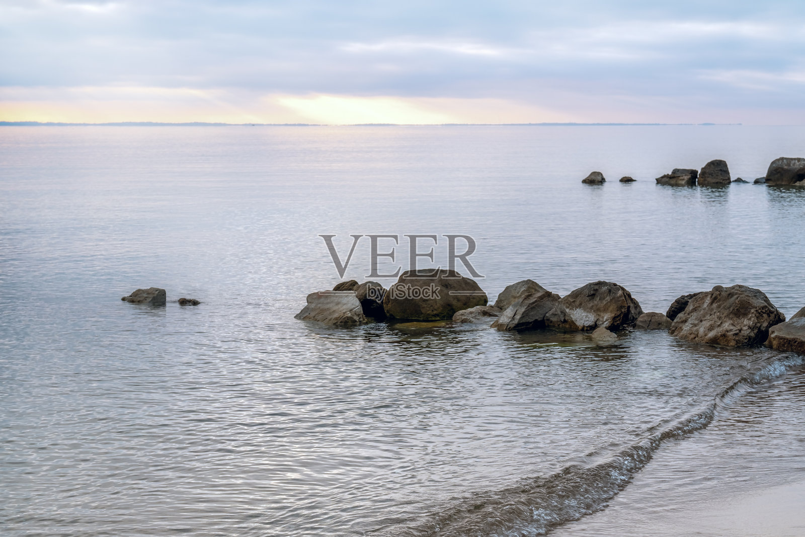 宁静的海岸线。沙滩和日落时的大石头照片摄影图片