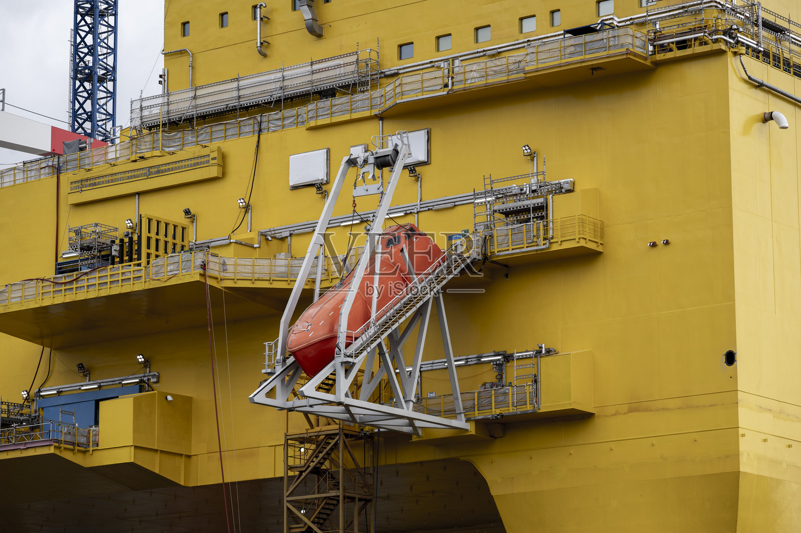 近距离拍摄的救生筏，紧贴在一座巨大的北海海上石油平台旁边照片摄影图片