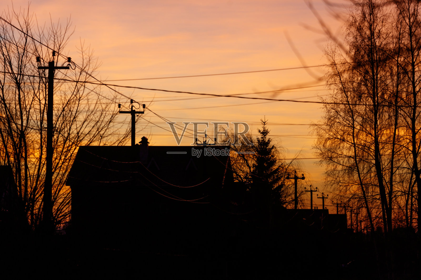 一栋黑色屋顶的房子在美丽的日落背景下呈现剪影。照片摄影图片