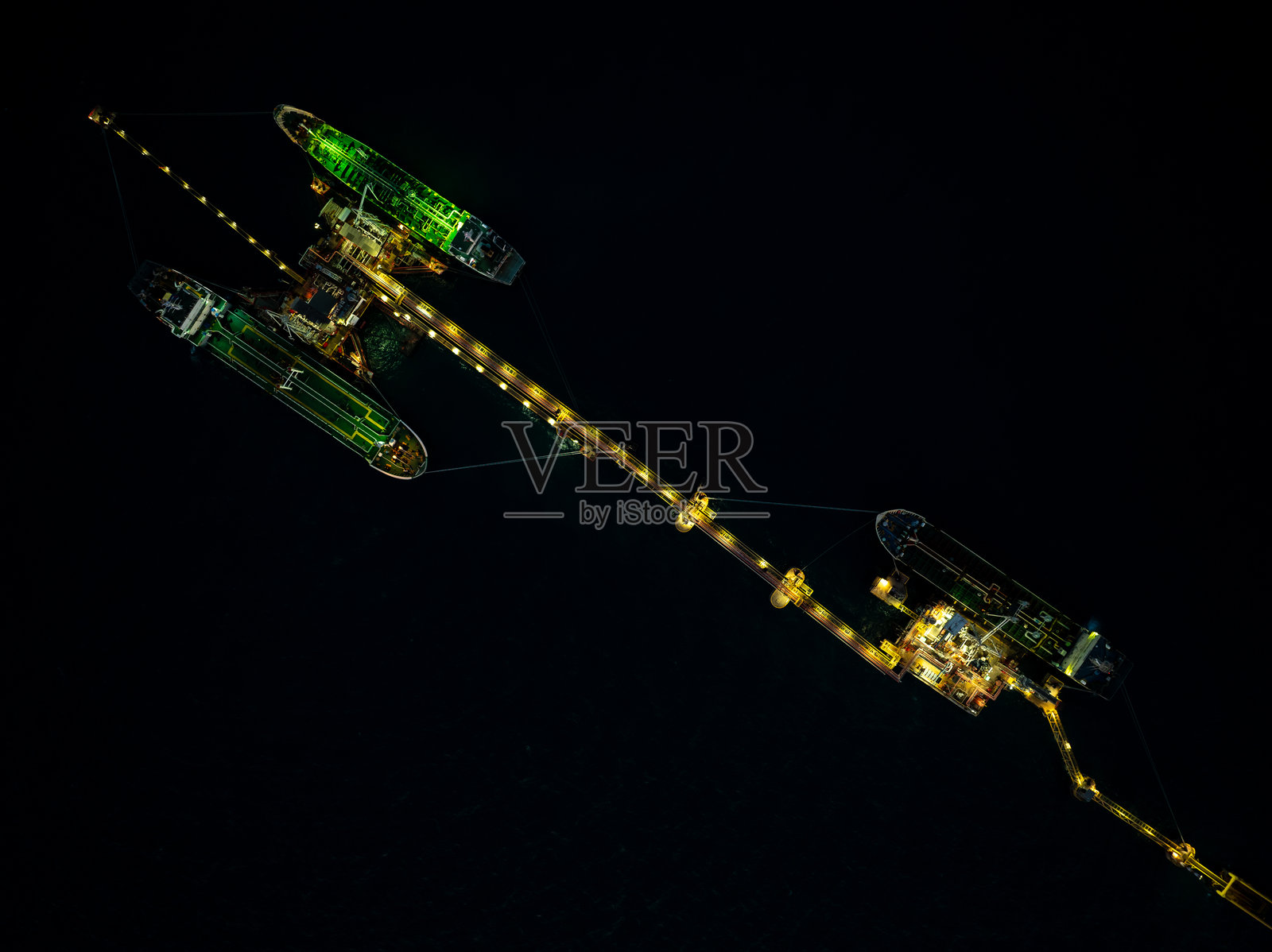 海上油气站的夜景，油轮正在装卸货物，体现进出口运输概念。照片摄影图片