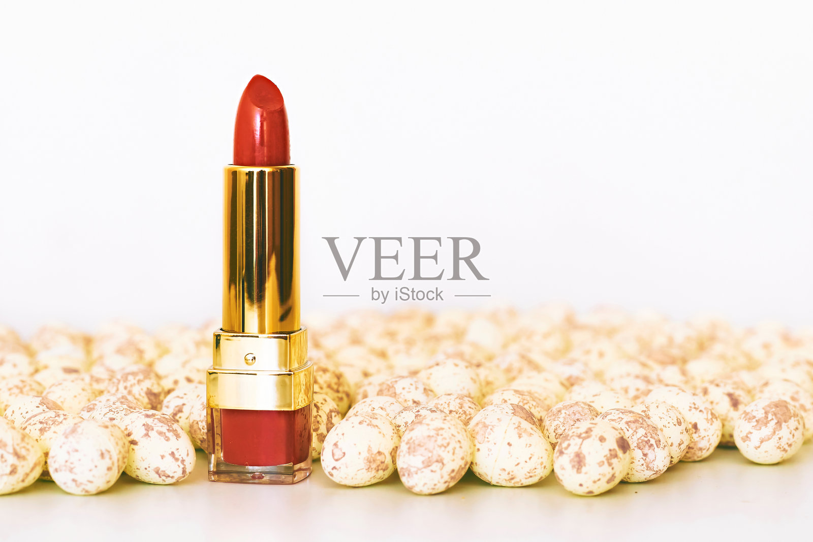 红色和粉色的化妆唇膏放在白色斑点的卵石上照片摄影图片