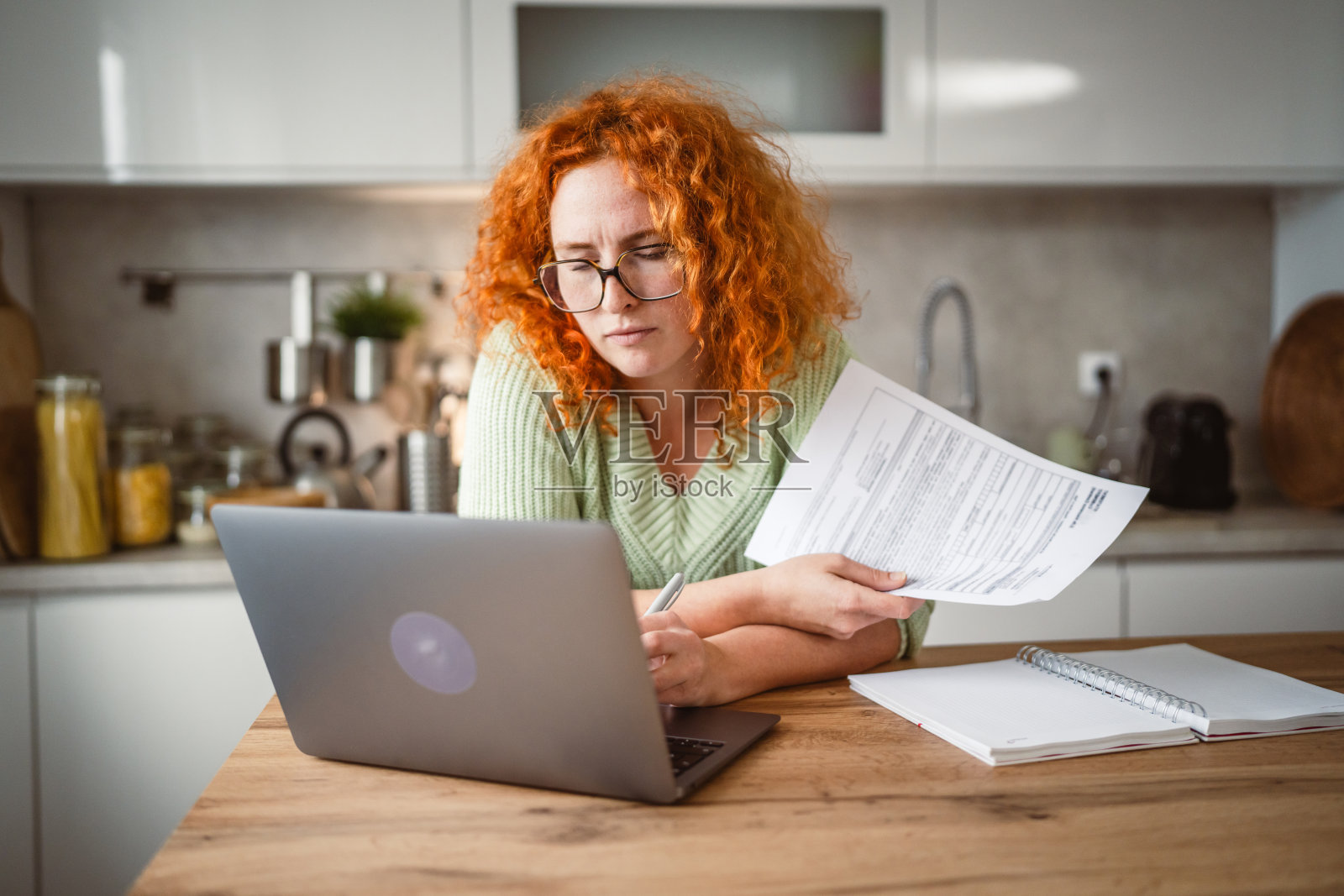 疲惫的成年女性在家中使用笔记本电脑和记事本工作照片摄影图片