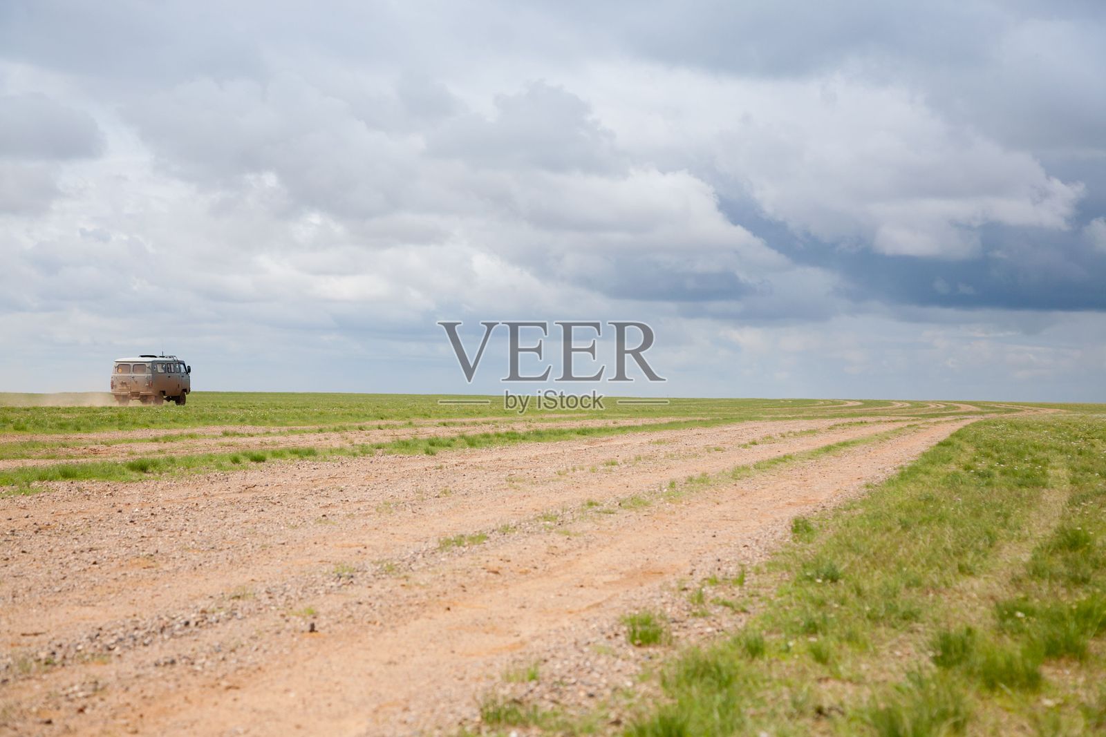 复古面包车在开阔草原上的土路上。照片摄影图片