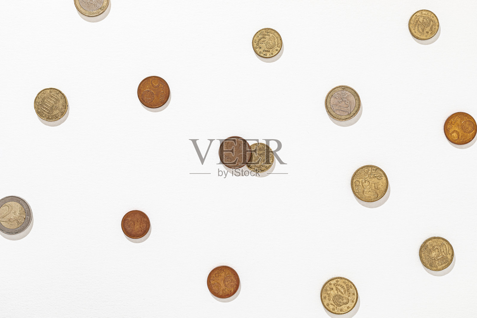 散落在白色纹理背景上的欧洲硬币，展示不同面值照片摄影图片