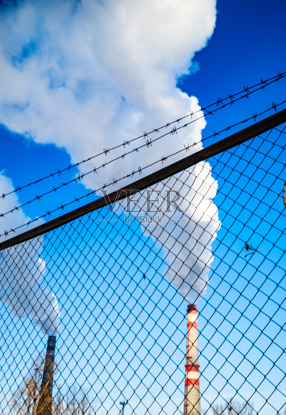 铁丝网围栏后的工业烟囱照片摄影图片