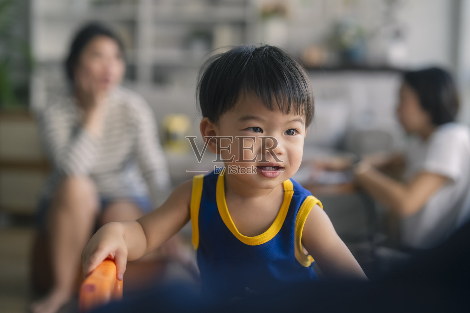 可爱的亚洲小男孩穿着运动服，在客厅里快乐地奔跑、玩耍和大笑。照片摄影图片